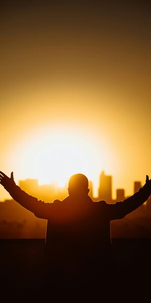 Man praying with the sunrise infront over a city