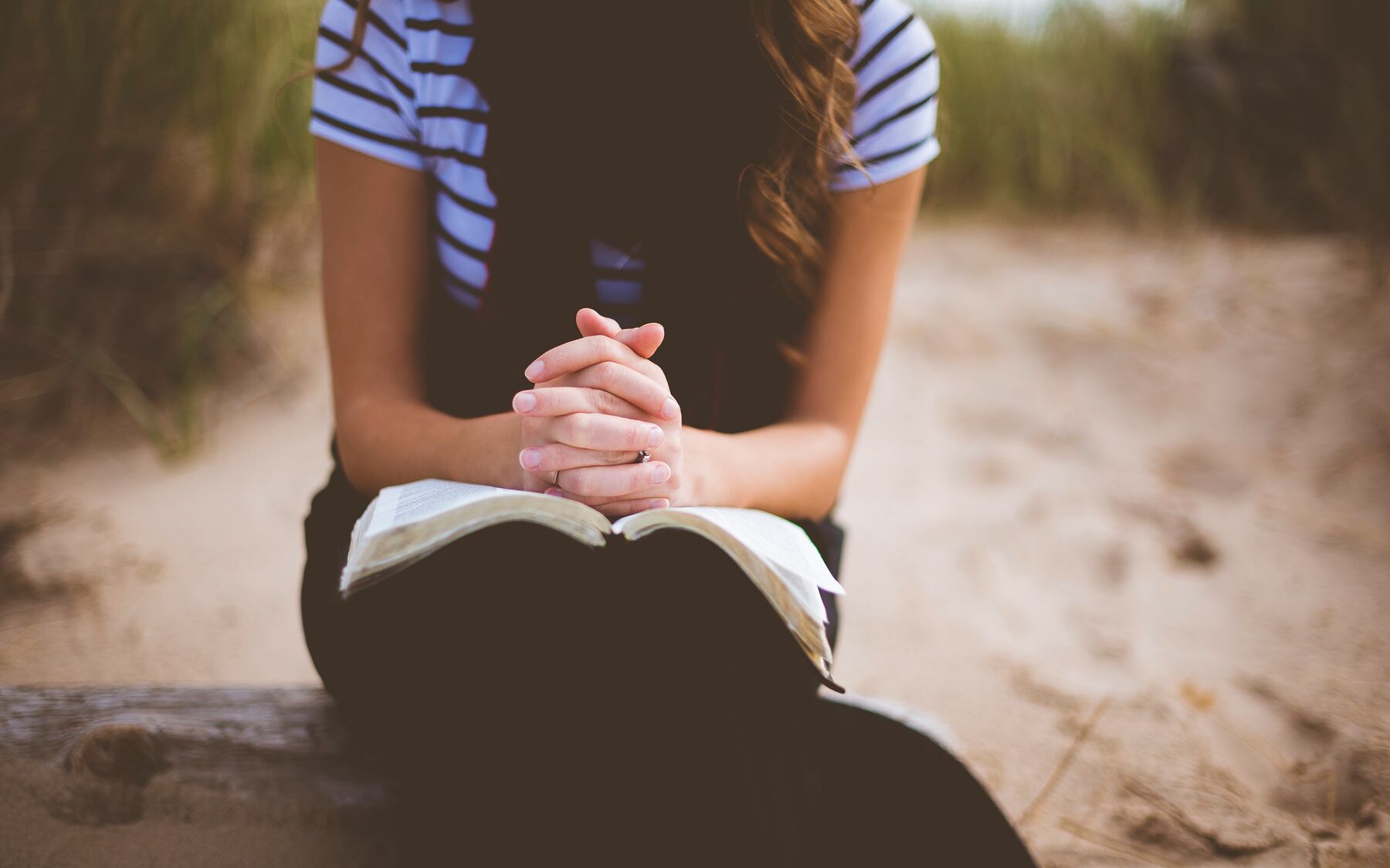 Woman praying on bench with bible