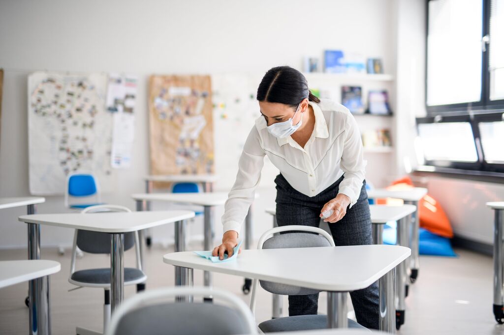 Teacher cleaning desks min