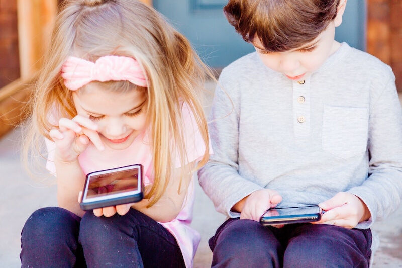 two young children looking at iphone's