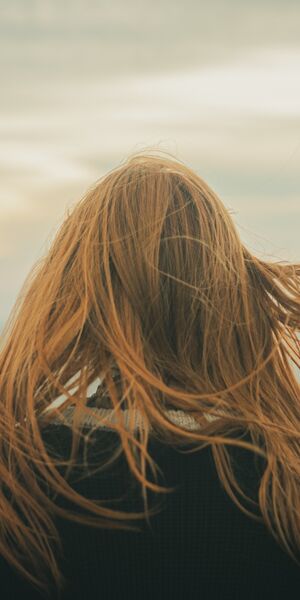 back of a woman's head as she looks out to sea