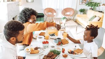 smiling parents and child eat together at a table