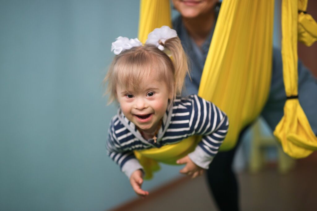 Little girl with Down syndrome held in a yellow sling