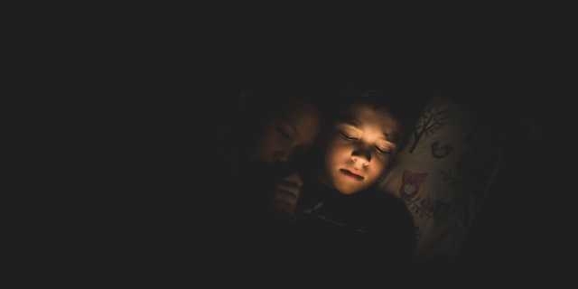 boy in darkness watching ipad