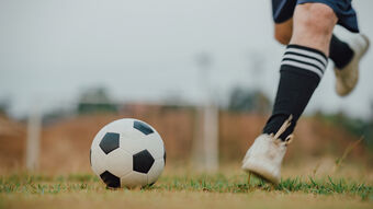 footballer running towards football