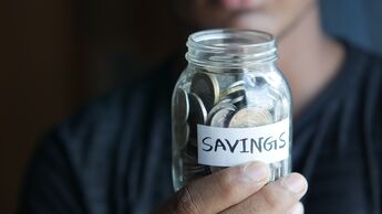 Man holding a jar of pennies with a 'savings' label on it