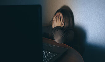 Teenager on computer dark embarrased covering face