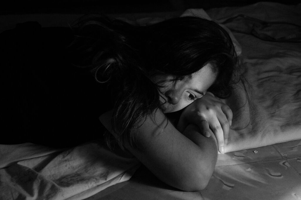 Sad woman lying in bed