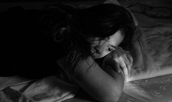 Sad woman lying in bed