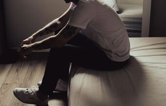 Man sad sitting on bed